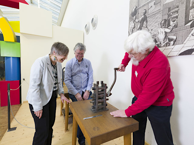 Ehrenamtlicher bedient die Münzprägestation im Museum